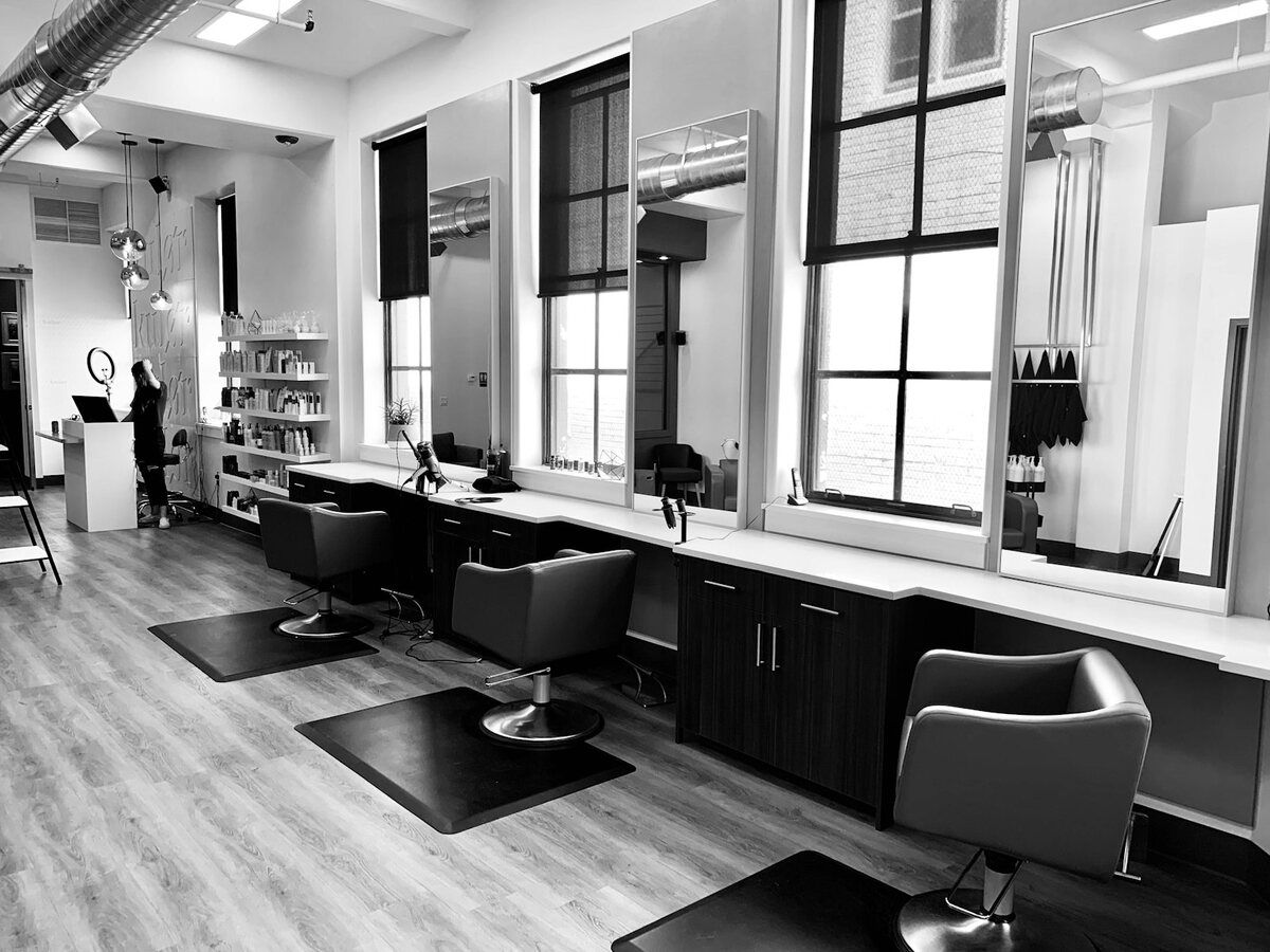 Salón de belleza con sillones, espejos y grandes ventanales